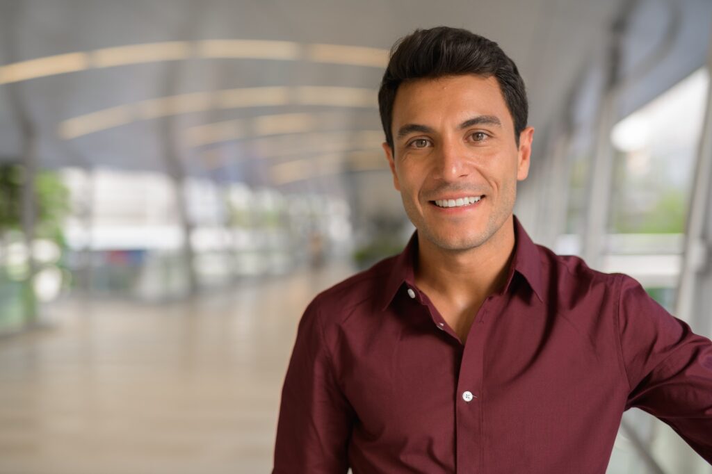 Face of happy Hispanic businessman smiling on the footbridge